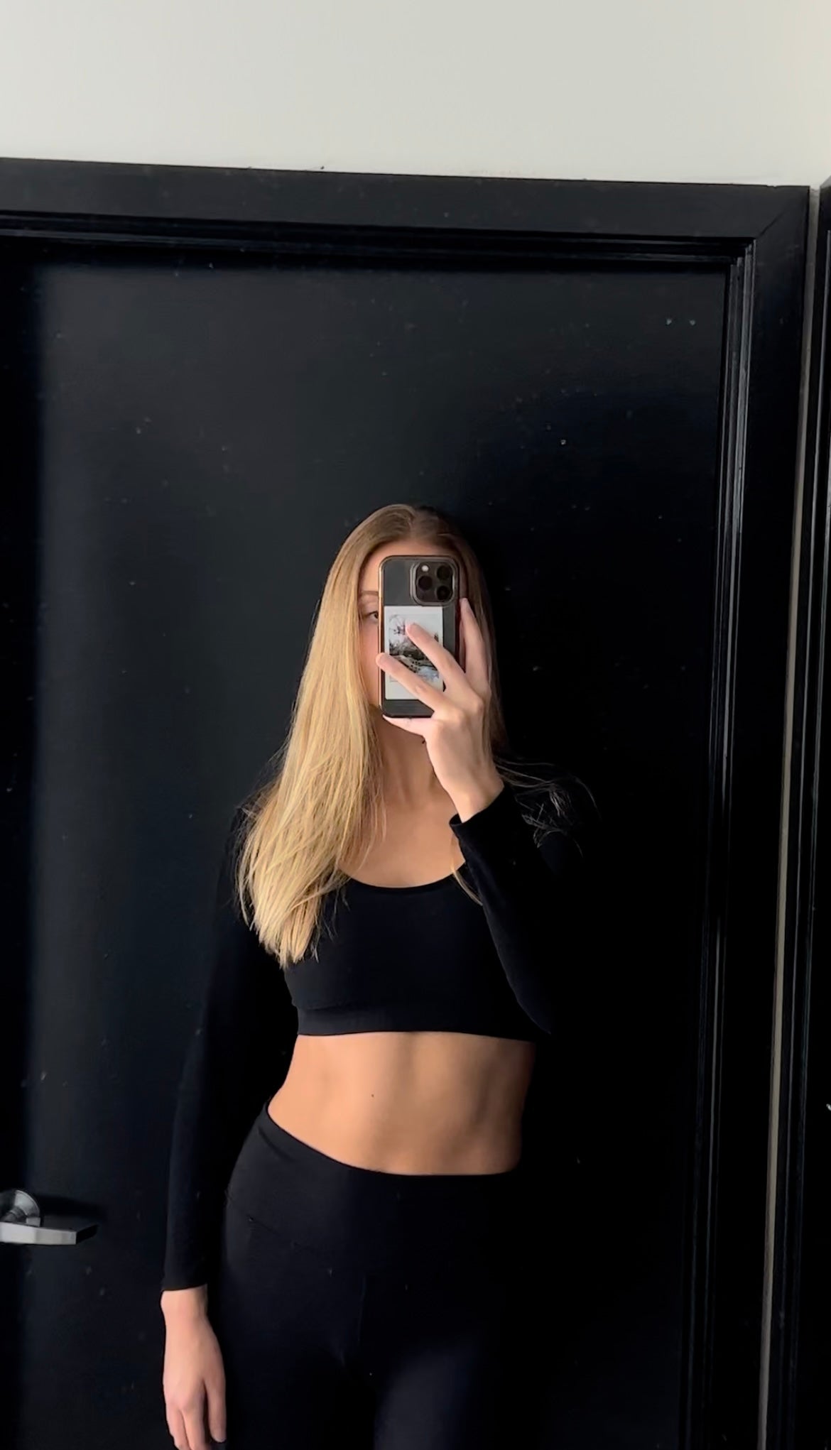 Girl posing in a mirror wearing activewear clothes and showing her abs/core. 